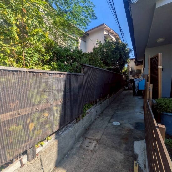 川西市南花屋敷│庭木に圧迫されて傾いているフェンス